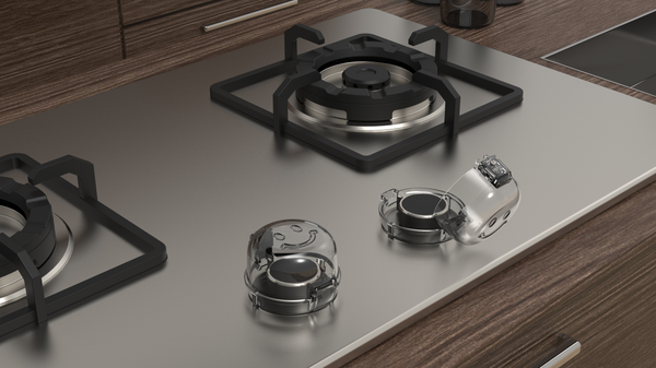 Secure Cuddle gas stove knob cover in clear polycarbonate shown on a stovetop to keep children from knobs